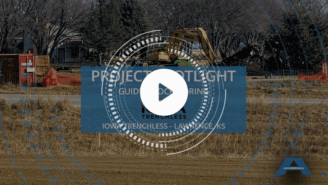 Trenchless construction site in Kansas featuring large tunneling equipment, with play button overlay for project video.